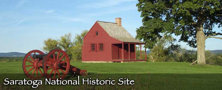 A cannon sits in front of a small cabin at Saratoga National Historic Site